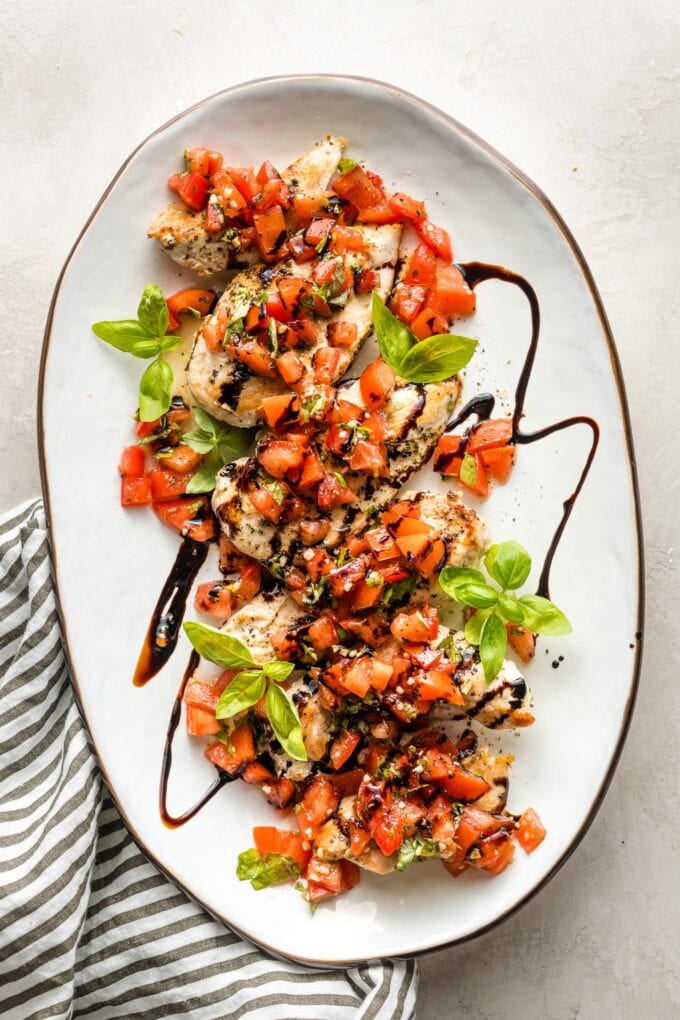 White platter filled with bruschetta chicken, ready to serve.