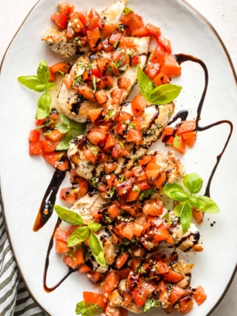 White platter filled with bruschetta chicken, ready to serve.