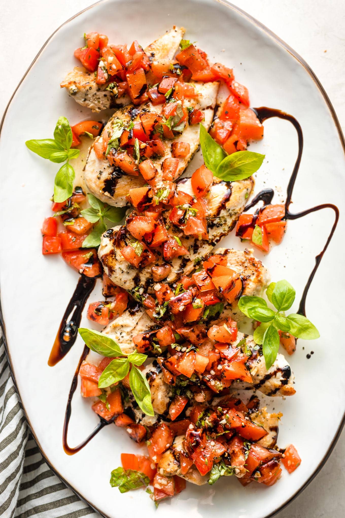 White platter filled with bruschetta chicken, ready to serve.