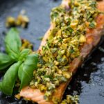 Close-up of pistachio herb salmon with a basil garnish.
