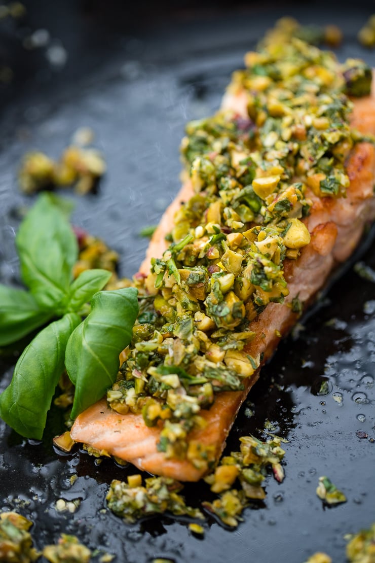 Close-up of pistachio herb salmon with a basil garnish.