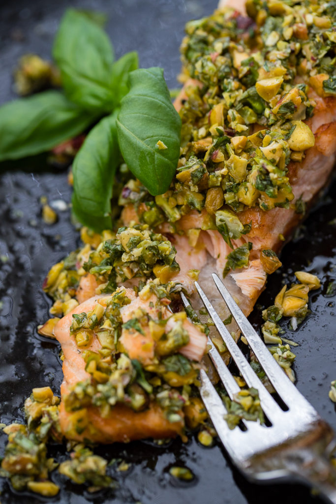 Close-up of pistachio herb salmon being flaked with a fork.