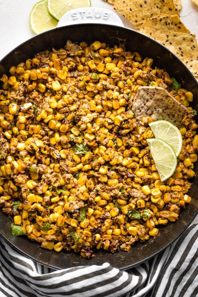 Cast iron skillet full of hot corn dip, surrounded by tortilla chips.