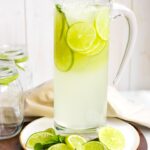 A tall glass pitcher filled with sparkling limeade.