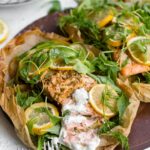 Lemon salmon with potatoes and zucchini, served with fresh arugula and herbs and a dill yogurt sauce.