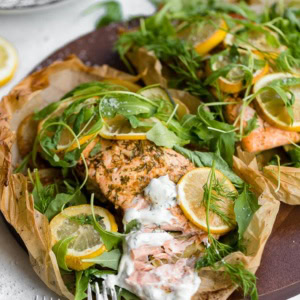 Lemon salmon with potatoes and zucchini, served with fresh arugula and herbs and a dill yogurt sauce.