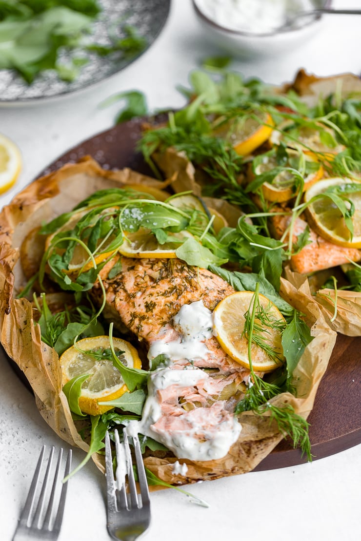 Close-up of parchment lemon salmon, baked and served with a Greek yogurt dill sauce.