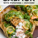 Parchment salmon baked with lemon slices, zucchini, potatoes, and the best light sauce makes an impressive, easy recipe for entertaining, date night, or any night! With a step-by-step visual guide on folding parchment packets - so much easier than you think! #parchmentfish #parchmentsalmon #recipesforentertaining