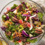 Apple cabbage slaw with shredded carrots and a brown sugar cider vinaigrette, served in a clear glass bowl.