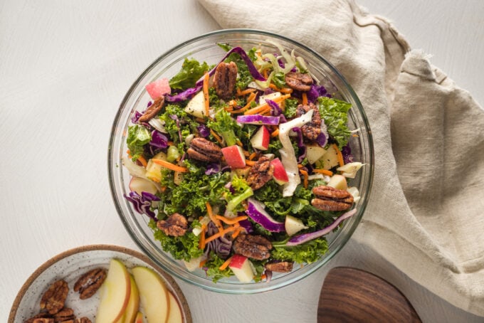 Apple cabbage slaw with shredded carrots and a brown sugar cider vinaigrette, served in a clear glass bowl.