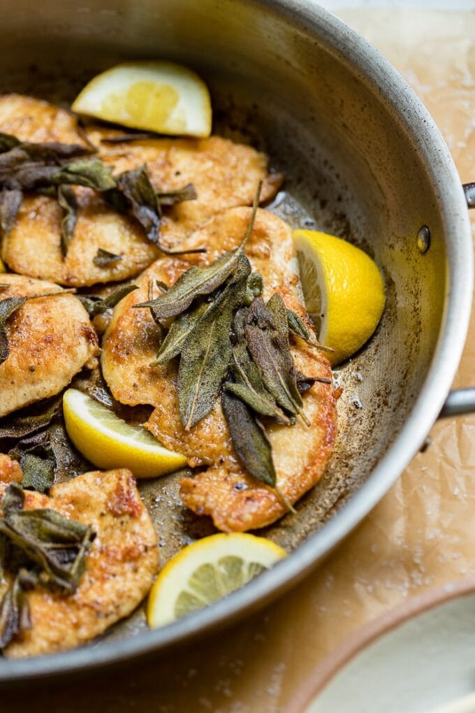 Close-up of a chicken breast cooked in a skillet with sage-infused brown butter.