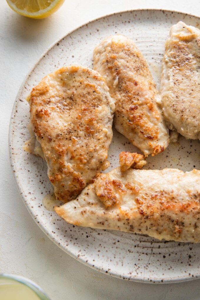 Seared chicken breasts resting on a white plate.