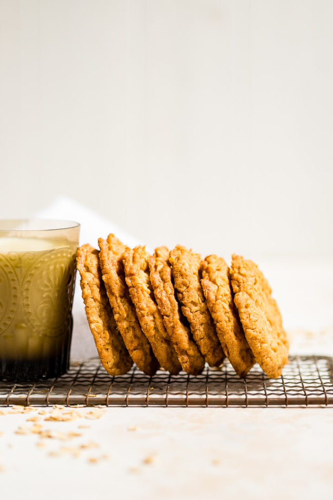 Crisp oatmeal cookies leaning on a glass of milk.