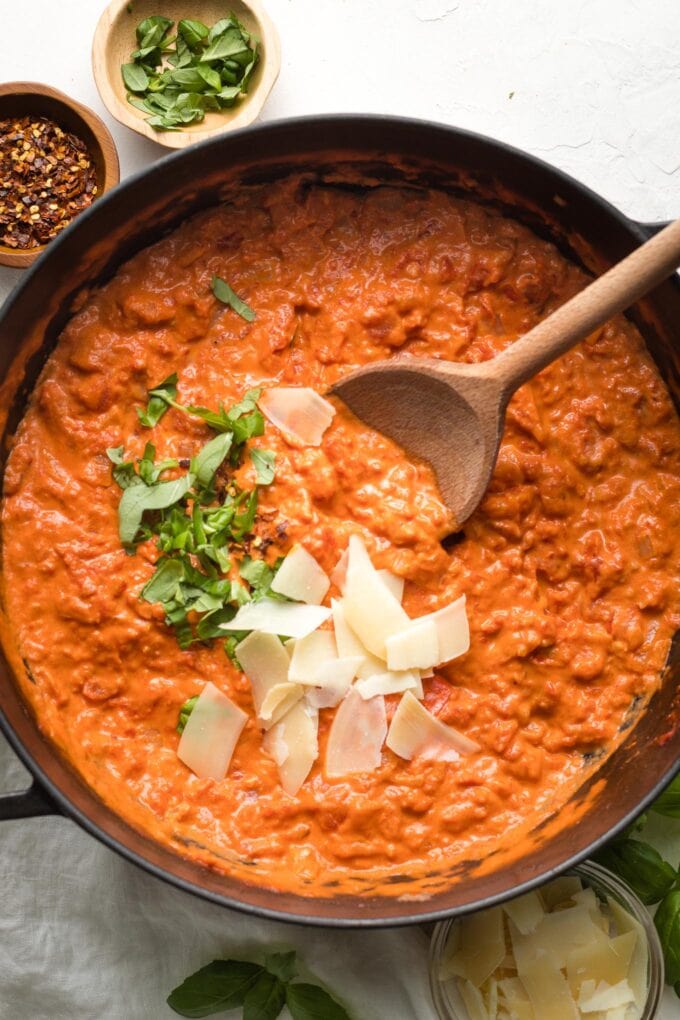 Close-up of homemade vodka sauce in a pan, sprinkled with extra basil and Parmesan cheese.