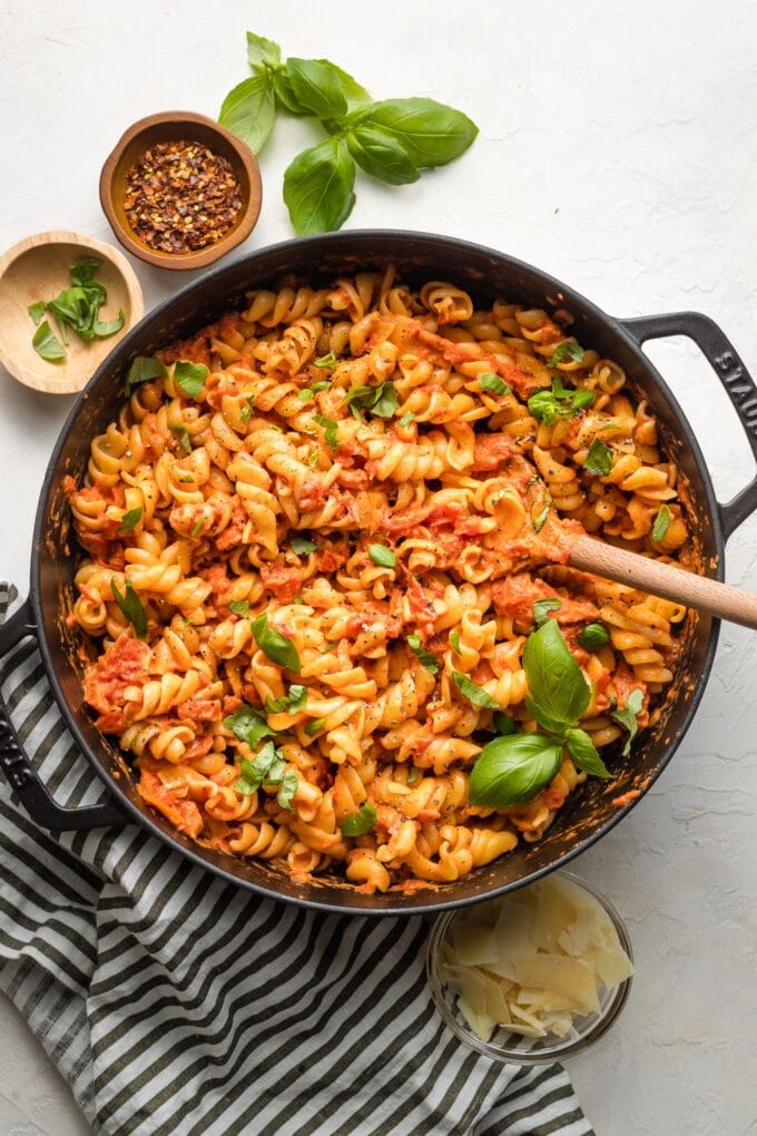 Rotini with homemade vodka sauce in a pan, garnished with basil.