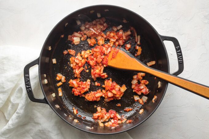 Tomato paste and diced onion cooking in a pan.