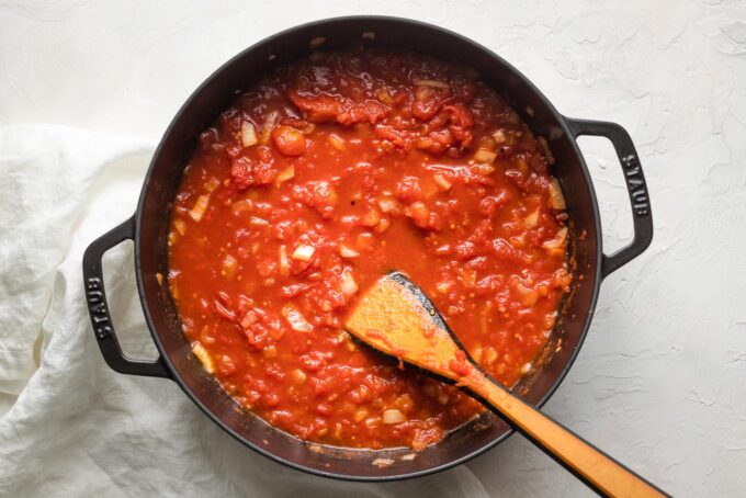 Whole tomatoes crushed and added to the pan.