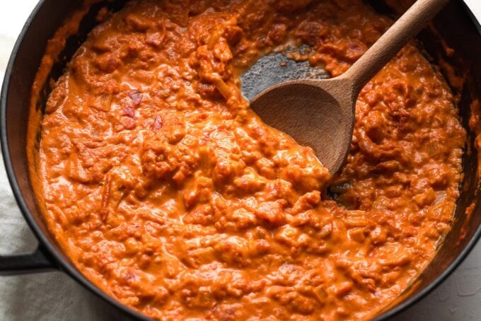 Close-up of homemade vodka sauce being stirred with a wooden spoon.