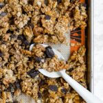 A large baking sheet filled with honey walnut granola with chocolate and cinnamon.