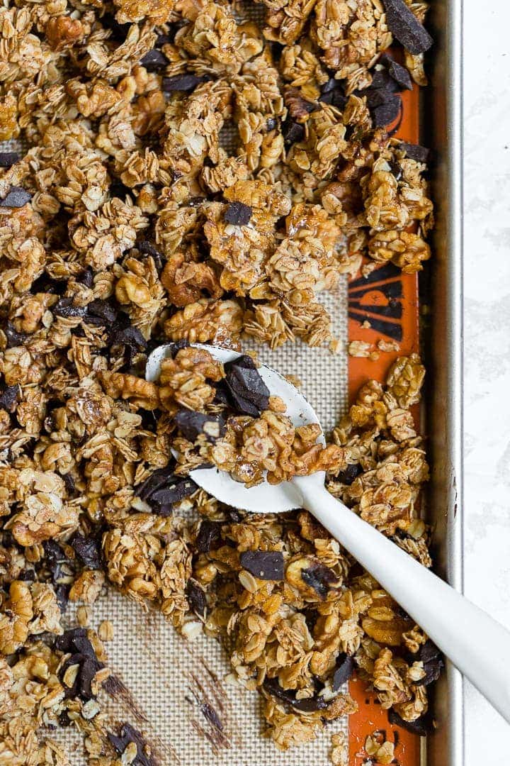 A large baking sheet filled with honey walnut granola with chocolate and cinnamon.