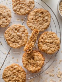 Cooling rack full of thin oatmeal cookies, with tender centers and lacy, golden brown edges.