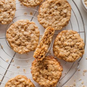 Cooling rack full of thin oatmeal cookies, with tender centers and lacy, golden brown edges.
