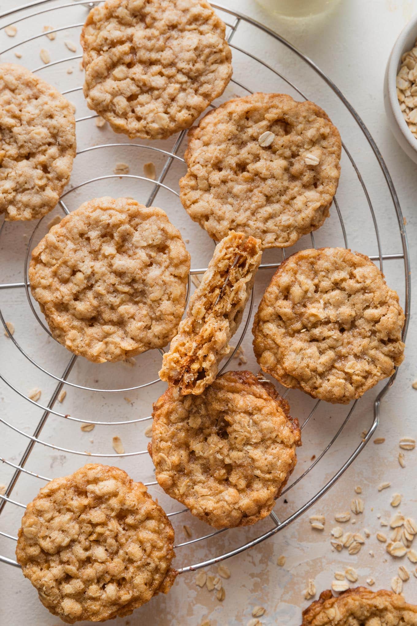 Cooling rack full of thin oatmeal cookies, with tender centers and lacy, golden brown edges.