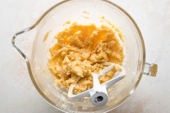 Cookie dough beat together in a clear glass stand mixer bowl.