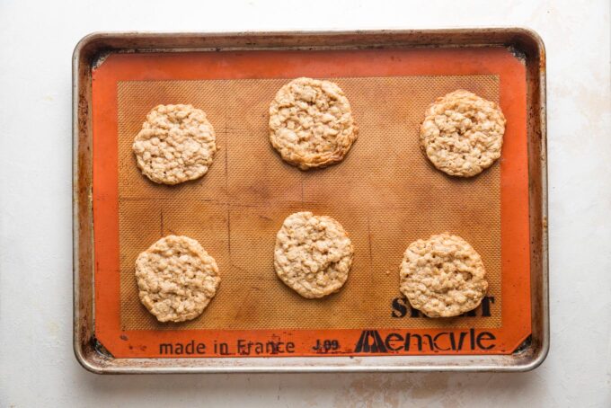 Baked oatmeal cookies cooling on the baking sheet.