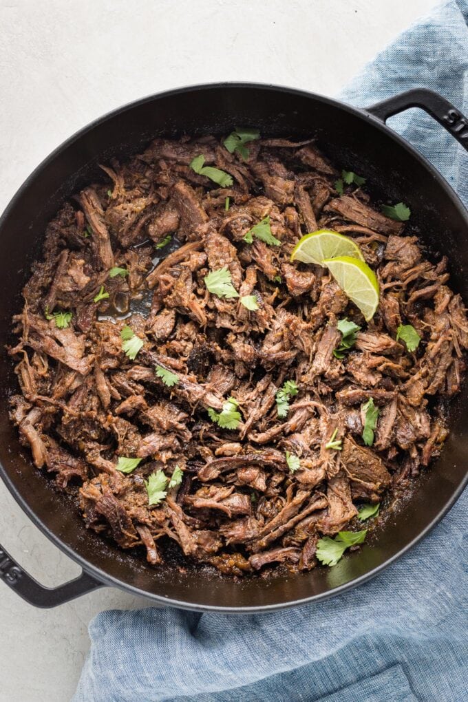 Cast iron skillet full of braised, shredded barbacoa.