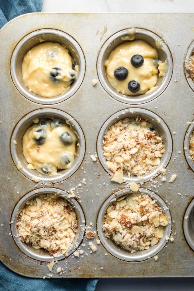 Batter divided among muffin tin wells, with streusel topping sprinkled on half.