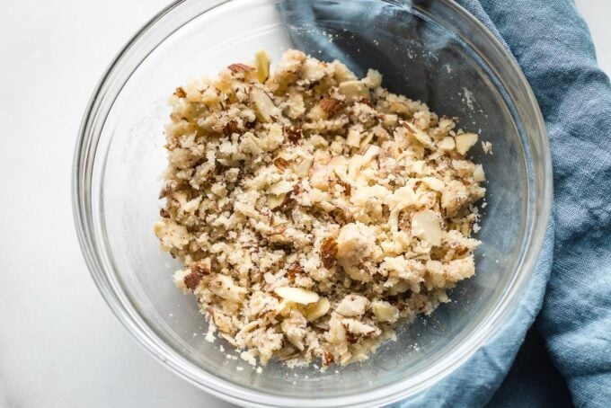 Clear glass prep bowl holding almond streusel topping.