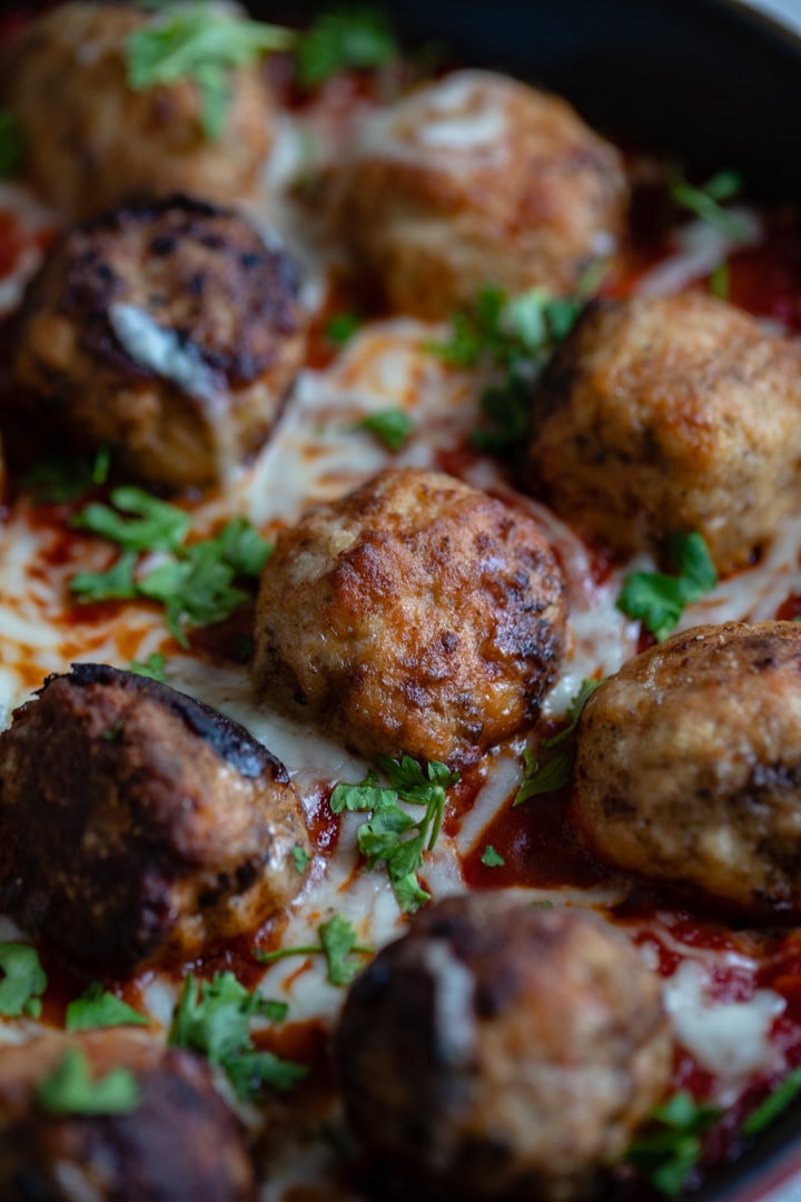 Close-up image of chicken Parmesan meatballs in the pan.