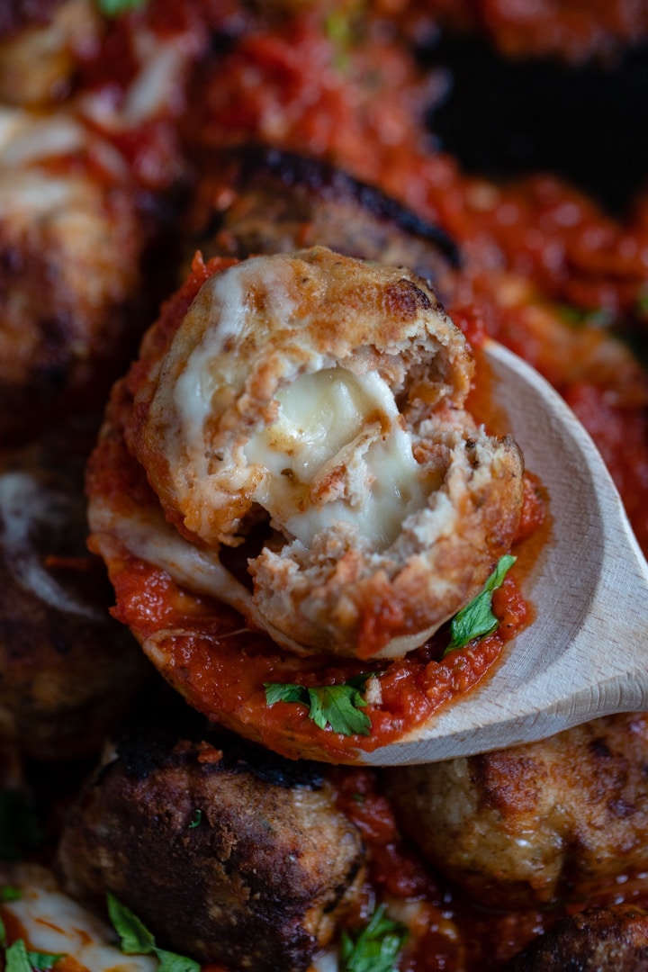 A meatball split open to reveal melted mozzarella inside.