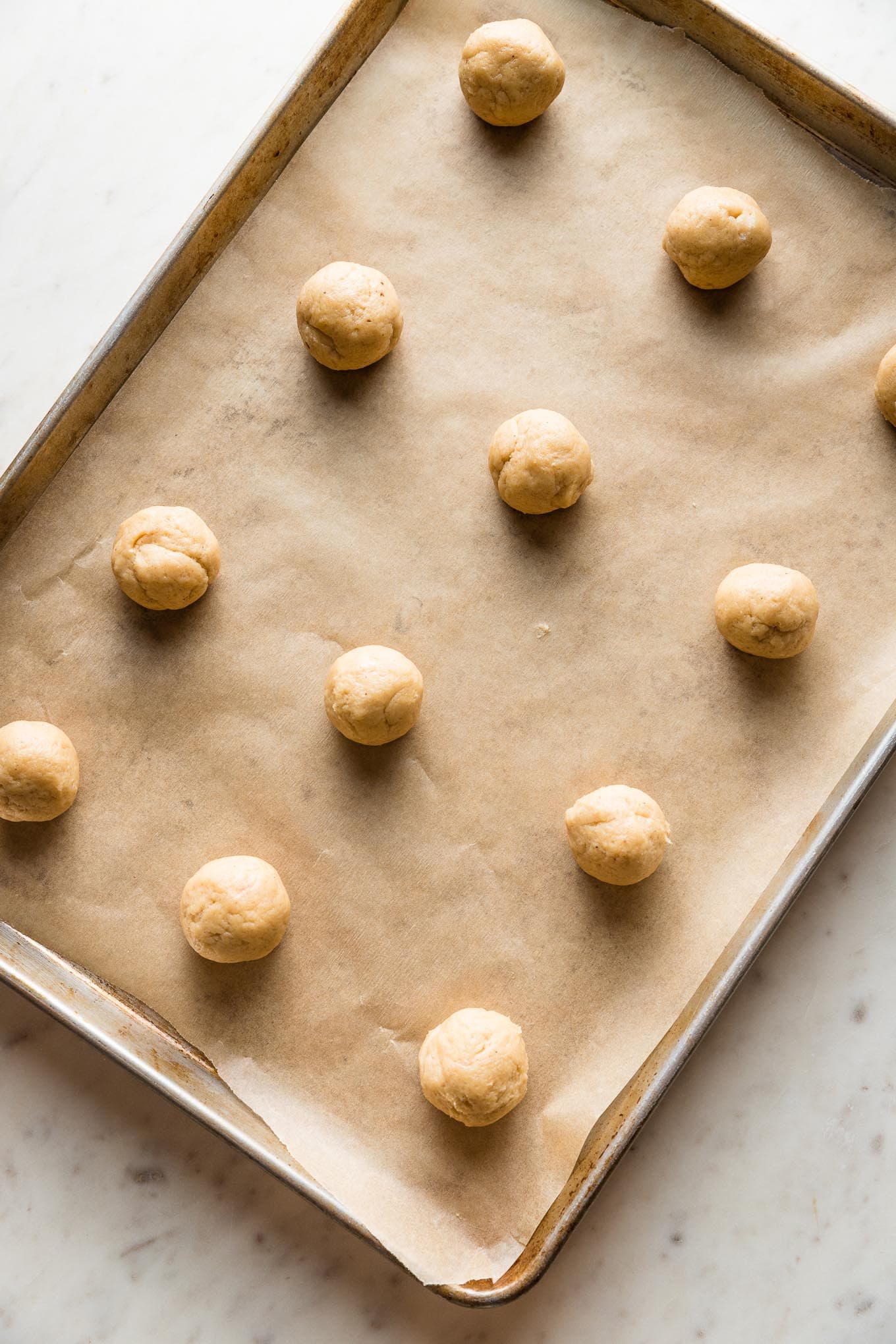 Rolled balls of eggnog sugar cookie dough, ready to bake.