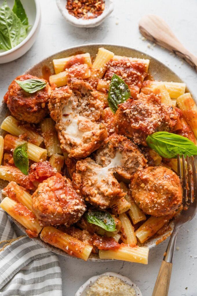 Plate with mozzarella-stuffed chicken meatballs served over rigatoni with marinara and Parmesan.