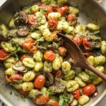 Skillet with gnocchi, pesto, mushrooms, and charred cherry tomatoes.