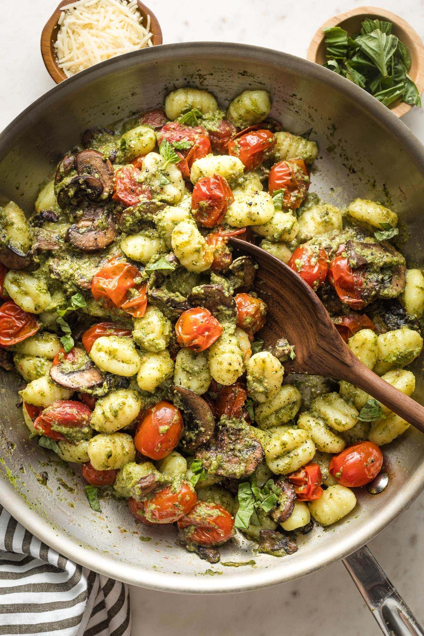 Skillet with gnocchi, pesto, mushrooms, and charred cherry tomatoes.