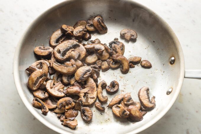 Mushrooms cooking in a skillet.