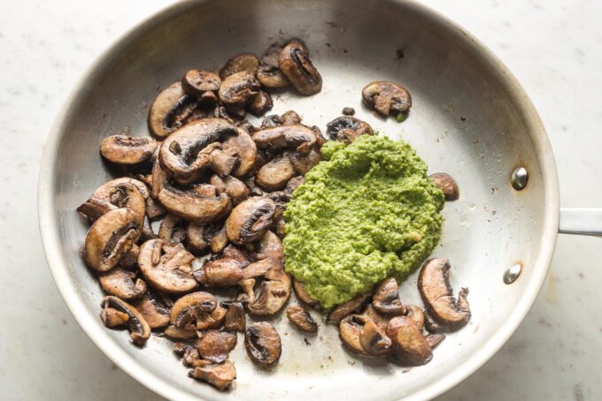 Pesto added to the skillet with mushrooms.