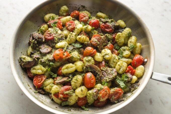 Skillet with gnocchi pesto all mixed together.