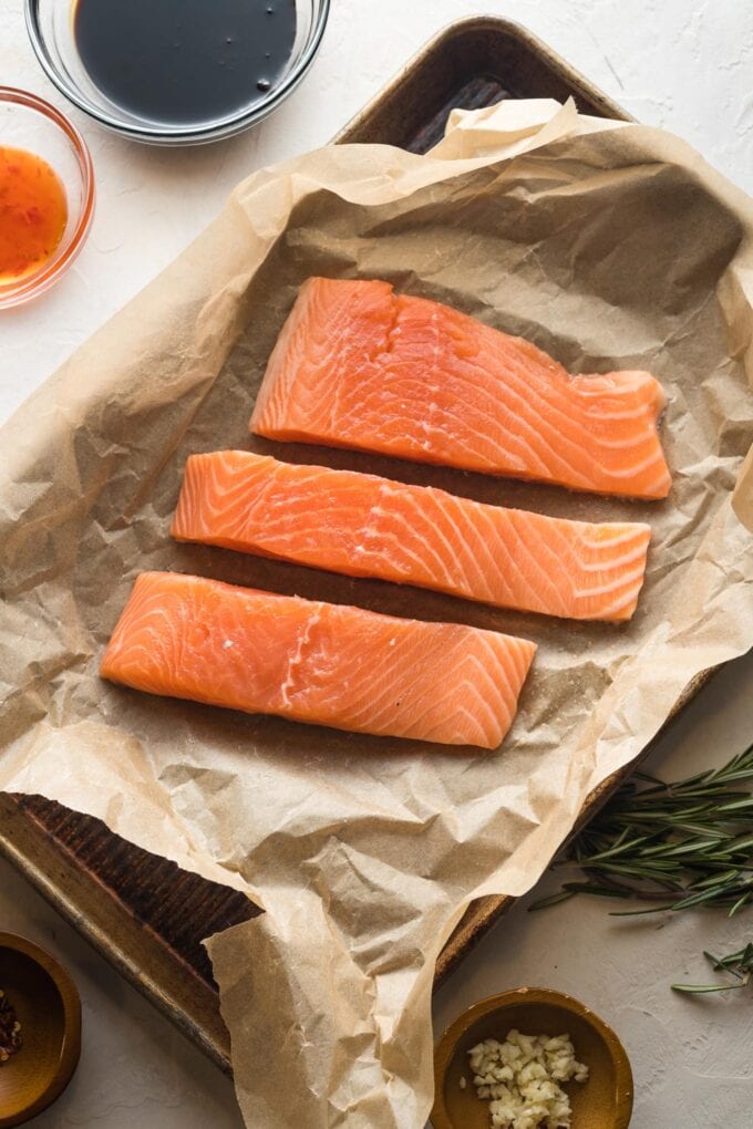 Salmon filets on a parchment-lined baking sheet.