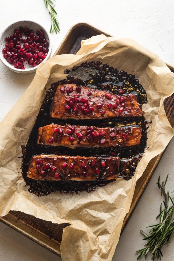 Baked pomegranate salmon on a pan and sprinkled with pomegranate arils.