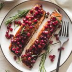 Plate with two filets of pomegranate salmon garnished with fresh rosemary.