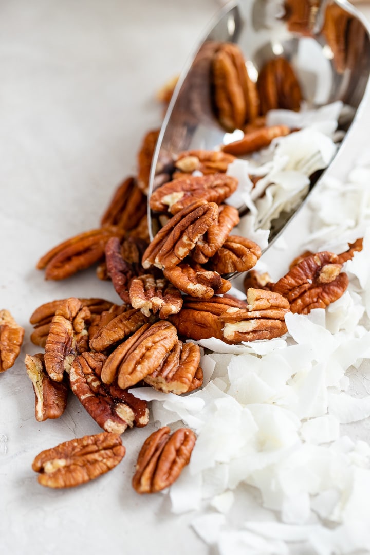 Close-up of whole pecans and unsweetened coconut flakes.