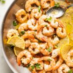 Spoon pouring sauce over garlic butter shrimp.