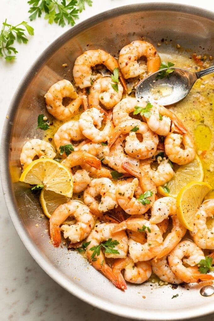 Spoon pouring sauce over garlic butter shrimp.