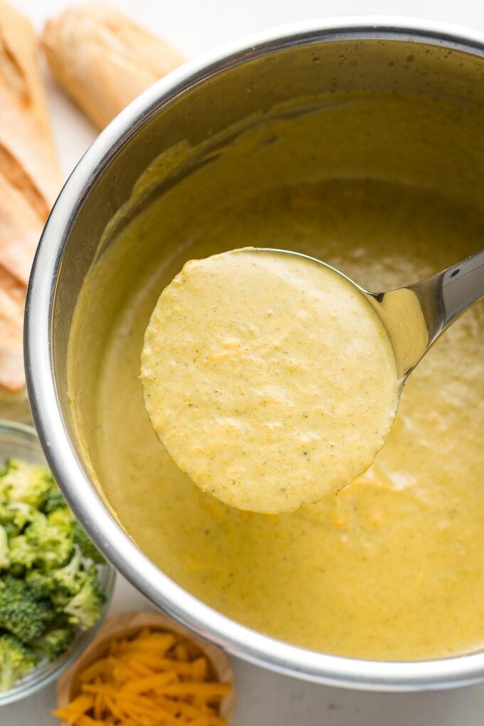 Ladle lifting broccoli cheddar soup out of an Instant Pot.