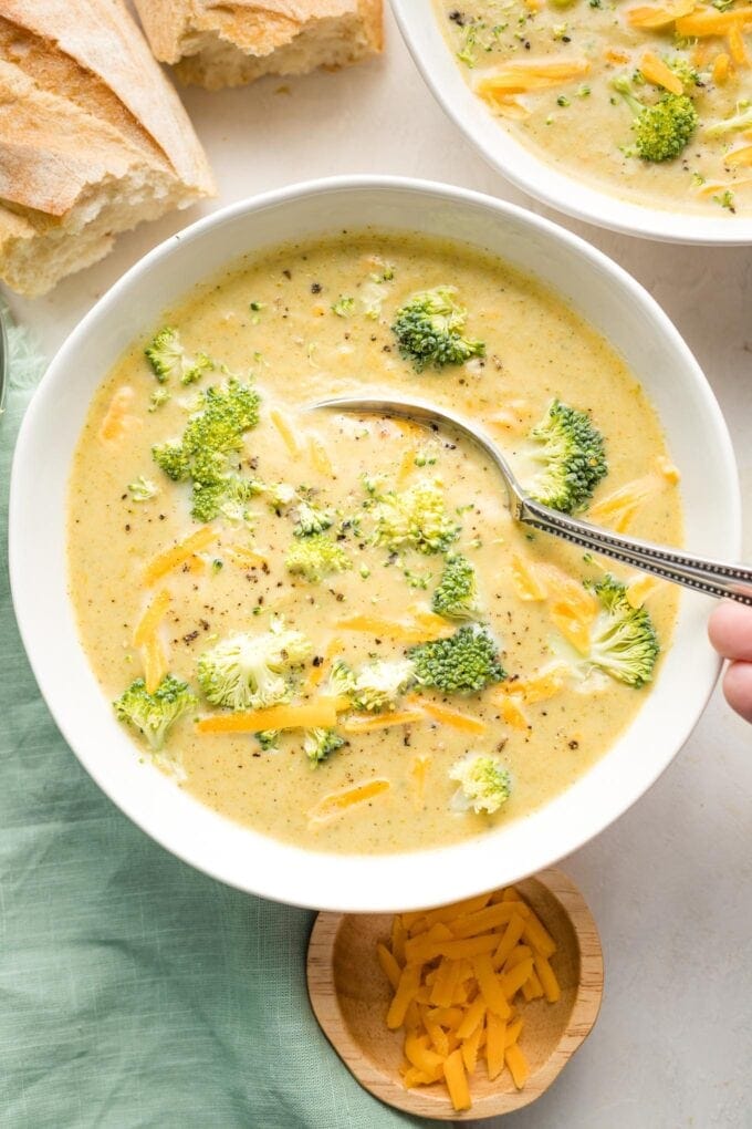 Spoon dipping into a bowl of broccoli cheddar soup.