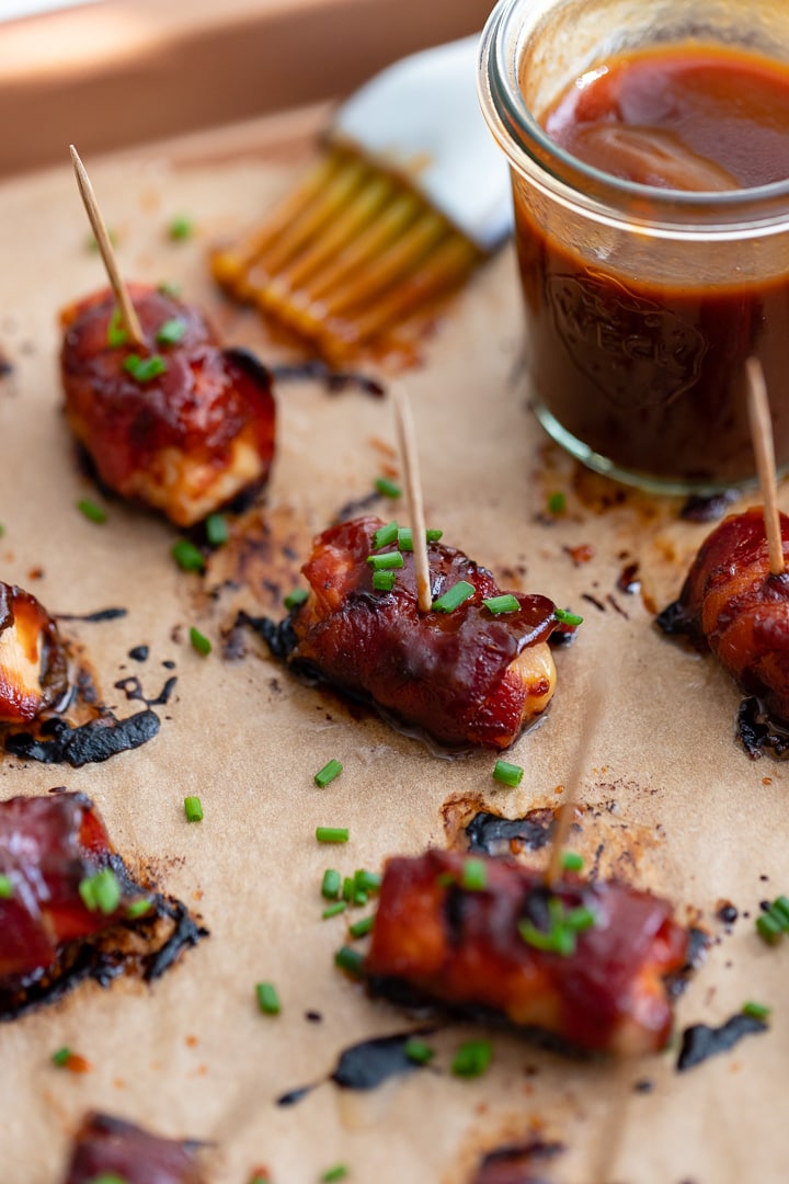 Close up of a chicken bacon BBQ bite slathered in BBQ sauce and garnished with chives.